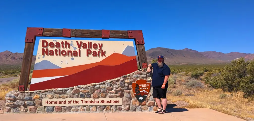 WanderBeard Standing At Death Valley National Park Sign At Nevada Entrance On Highway 374